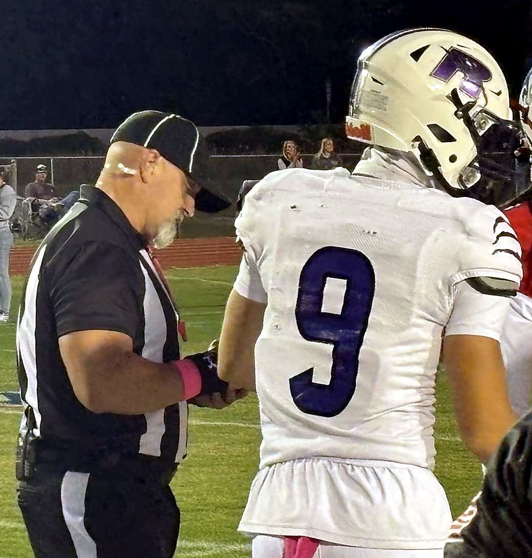 Brynnum Chaney, wearing white No. 9 for Rosepine, stands at midfield next to an official before the game.
